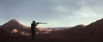Movie still from “The Mandalorian” (2019), created by Jon Favreau – A man standing in the desert holding a rifle; Extreme Wide shot, High angle