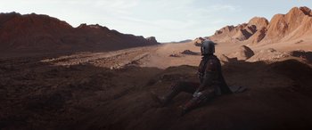 Movie still from “The Mandalorian” (2019), created by Jon Favreau – A man in a space suit sitting on the ground; Wide shot, High angle