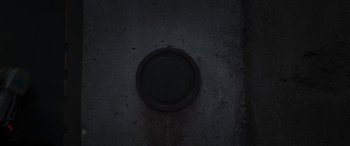 Movie still from “The Mandalorian” (2019), created by Jon Favreau – A black button on the side of a wall; Extreme Close Up shot, Overhead angle
