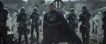 Movie still from “The Mandalorian” (2019), created by Jon Favreau – A group of men in star wars costumes standing next to each other; Medium shot, Over the shoulder angle