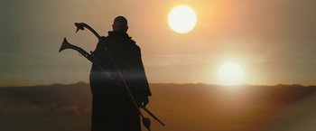 Movie still from “The Mandalorian” (2019), created by Jon Favreau – A man holding a spear and a spear in his hand; Wide shot, Low angle