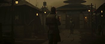 Movie still from “The Mandalorian” (2019), created by Jon Favreau – A man standing on a street looking at a building; Wide shot, Over the shoulder angle