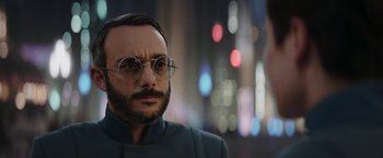 Movie still from “The Mandalorian” (2019), created by Jon Favreau – A man with a beard and glasses is looking at the camera; Close Up shot, Over the shoulder angle