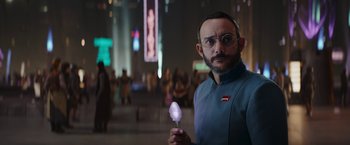 Movie still from “The Mandalorian” (2019), created by Jon Favreau – A man holding a glowing object while standing next to a crowd; Medium shot, Over the shoulder angle