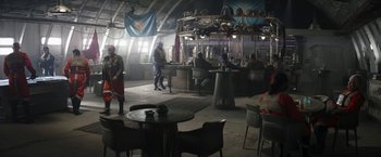 Movie still from “The Mandalorian” (2019), created by Jon Favreau – A group of people standing in a room with tables and chairs; Extreme Wide shot, Over the shoulder angle