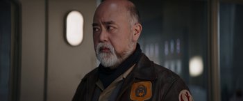 Movie still from “The Mandalorian” (2019), created by Jon Favreau – An older man with a beard and a leather jacket; Close Up shot, Low angle