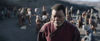 Movie still from “The Mandalorian” (2019), created by Jon Favreau – An older man wearing a red and brown robe; Close Up shot, Over the shoulder angle