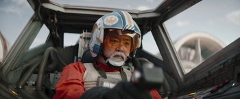 Movie still from “The Mandalorian” (2019), created by Jon Favreau – An older man in a star wars costume in a vehicle; Close Up shot, Over the shoulder angle