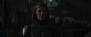A woman with red hair is standing in the dark