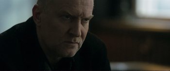 Movie still from “The Marco Effect” (2021), directed by Martin Zandvliet – An older man with a goatee stares into the camera; Close Up shot, Over the shoulder angle