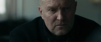 Movie still from “The Marco Effect” (2021), directed by Martin Zandvliet – An older man with a goatee looking at the camera; Close Up shot, Low angle