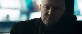 Movie still from “The Marco Effect” (2021), directed by Martin Zandvliet – An older man with a goatee looking at the camera; Close Up shot, Low angle