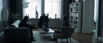 Movie still from “The Marco Effect” (2021), directed by Martin Zandvliet – A group of people sitting around a living room; Wide shot, Over the shoulder angle