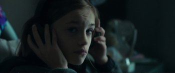Movie still from “The Marco Effect” (2021), directed by Martin Zandvliet – A young girl holding a cell phone up to her ear; Close Up shot, Over the shoulder angle