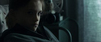 Movie still from “The Marco Effect” (2021), directed by Martin Zandvliet – A young woman sitting in a dark room looking at the camera; Close Up shot, Over the shoulder angle