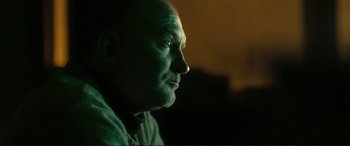 Movie still from “The Marco Effect” (2021), directed by Martin Zandvliet – A person's face in a dark room; Close Up shot, Low angle