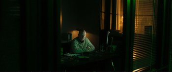 Movie still from “The Marco Effect” (2021), directed by Martin Zandvliet – A man sitting at a desk in a dark room; Medium shot, Low angle