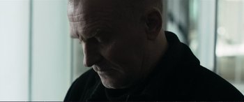 Movie still from “The Marco Effect” (2021), directed by Martin Zandvliet – A man with a shaved head is looking down; Close Up shot, Low angle