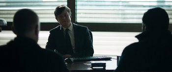 Movie still from “The Marco Effect” (2021), directed by Martin Zandvliet – A man sitting at a table in front of a computer keyboard; Medium shot, Over the shoulder angle