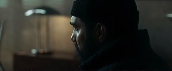 Movie still from “The Marco Effect” (2021), directed by Martin Zandvliet – A man with a beard wearing a black hat; Close Up shot, Over the shoulder angle