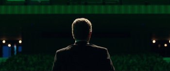 Movie still from “The Marco Effect” (2021), directed by Martin Zandvliet – A man in a black suit standing in front of a green screen; Medium shot, Low angle