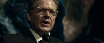 Movie still from “The Marco Effect” (2021), directed by Martin Zandvliet – An older man wearing glasses and a suit and tie; Close Up shot, Over the shoulder angle