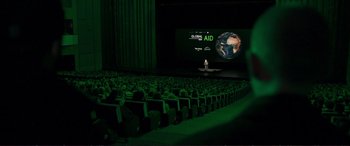 Movie still from “The Marco Effect” (2021), directed by Martin Zandvliet – An audience is watching a presentation in front of a large screen; Extreme Wide shot, High angle