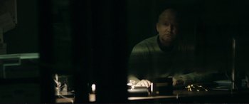 Movie still from “The Marco Effect” (2021), directed by Martin Zandvliet – A man sitting in front of a computer monitor; Medium shot, Over the shoulder angle