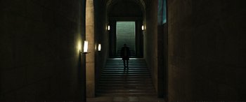 Movie still from “The Marco Effect” (2021), directed by Martin Zandvliet – A man standing in a dark hallway near a staircase; Extreme Wide shot, Low angle