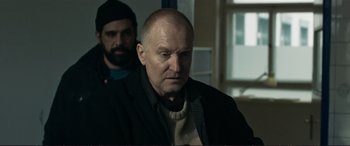 Movie still from “The Marco Effect” (2021), directed by Martin Zandvliet – A man in a black jacket and a bearded man in a black jacket; Medium shot, Over the shoulder angle