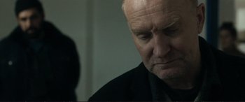 Movie still from “The Marco Effect” (2021), directed by Martin Zandvliet – An older man in a black shirt looking down at his face; Close Up shot, Over the shoulder angle