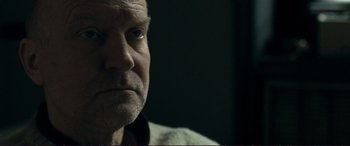 Movie still from “The Marco Effect” (2021), directed by Martin Zandvliet – A man's face in a dark room; Close Up shot, Over the shoulder angle