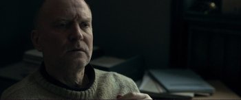 Movie still from “The Marco Effect” (2021), directed by Martin Zandvliet – An older man wearing a sweater looking at the camera; Close Up shot, Over the shoulder angle