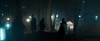 Movie still from “The Marco Effect” (2021), directed by Martin Zandvliet – A group of people standing in the woods at night; Extreme Wide shot, Low angle