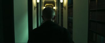 Movie still from “The Marco Effect” (2021), directed by Martin Zandvliet – A man with a shaved head is walking down a hallway; Medium shot, Low angle