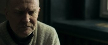 Movie still from “The Marco Effect” (2021), directed by Martin Zandvliet – An older man wearing a sweater and glasses; Close Up shot, Over the shoulder angle