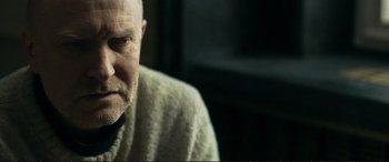 Movie still from “The Marco Effect” (2021), directed by Martin Zandvliet – An older man wearing a white sweater looking at the camera; Close Up shot, Over the shoulder angle