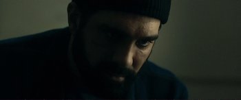 Movie still from “The Marco Effect” (2021), directed by Martin Zandvliet – A man with a beard wearing a black hat; Close Up shot, Over the shoulder angle