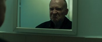 Movie still from “The Marco Effect” (2021), directed by Martin Zandvliet – An older man looking in the mirror with a frowning look on his face; Close Up shot, Low angle
