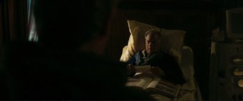 Movie still from “The Marco Effect” (2021), directed by Martin Zandvliet – An older man reading a book in a bed; Medium shot, Over the shoulder angle