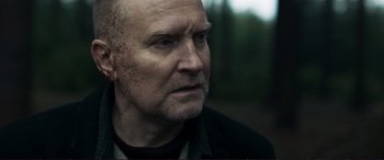 Movie still from “The Marco Effect” (2021), directed by Martin Zandvliet – An older man with a beard and a black jacket; Close Up shot, Over the shoulder angle