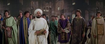 Movie still from “The Message” (1976), directed by Moustapha Akkad – A group of men in robes standing next to each other in a room; Medium shot, Low angle