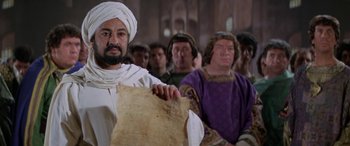 Movie still from “The Message” (1976), directed by Moustapha Akkad – A group of people in a room holding papers; Close Up shot, High angle