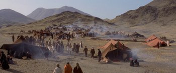 Movie still from “The Message” (1976), directed by Moustapha Akkad – A group of people walking through a field with tents; Extreme Wide shot, High angle