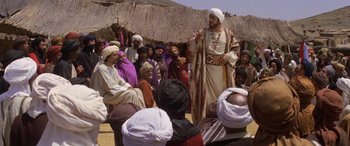 Movie still from “The Message” (1976), directed by Moustapha Akkad – A group of people that are sitting in the sand; Wide shot, High angle