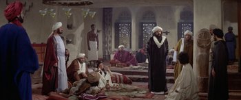 Movie still from “The Message” (1976), directed by Moustapha Akkad – A group of people sitting around a room; Wide shot, High angle