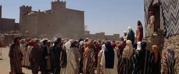 Movie still from “The Message” (1976), directed by Moustapha Akkad – A group of men in traditional clothing standing in front of a building; Extreme Wide shot, High angle