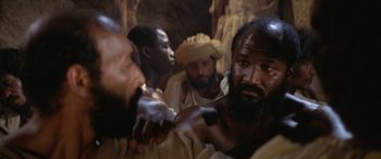 Movie still from “The Message” (1976), directed by Moustapha Akkad – A group of men standing next to each other in a room; Close Up shot, Low angle