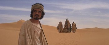 Movie still from “The Message” (1976), directed by Moustapha Akkad – A group of people in the desert with a man in the foreground; Medium shot, Low angle
