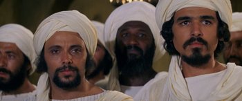 Movie still from “The Message” (1976), directed by Moustapha Akkad – A group of men in white robes and white hats; Close Up shot, High angle